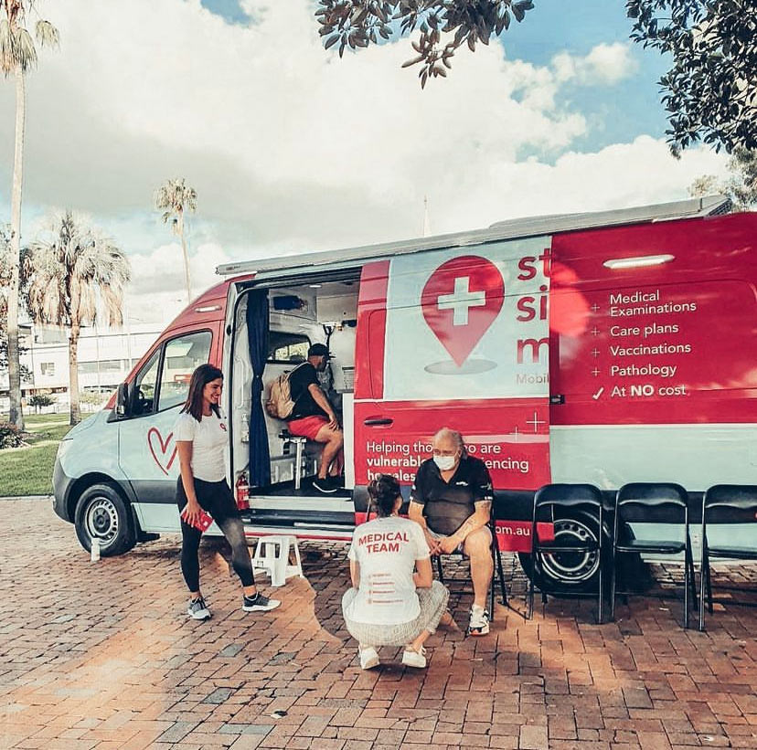 Medical van with people sitting in front of it.